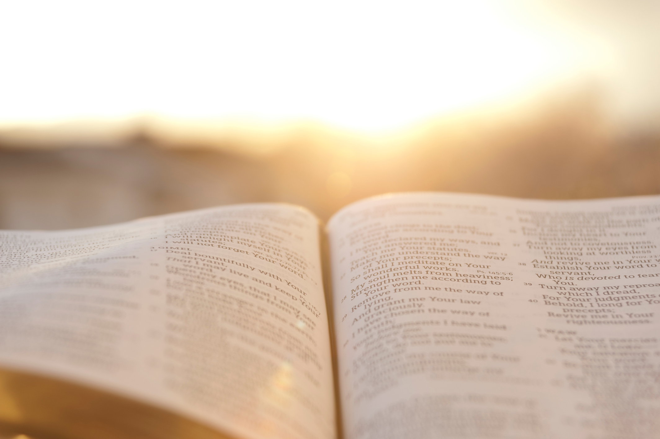 Open Bible with bright sunset in the background.